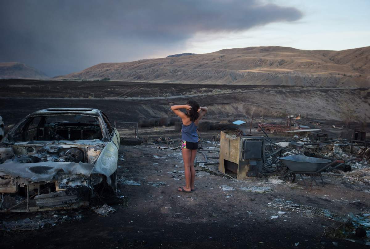 Nevaeh Porter, 8, reacts while viewing the remains of her home where she lived with her mom and grandparents that was destroyed by wildfire on the Ashcroft First Nation, near Ashcroft, B.C., late Sunday July 9, 2017. THE CANADIAN PRESS/Darryl Dyck