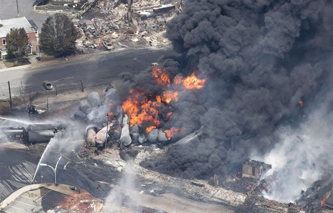 Smoke rises from railway cars that were carrying crude oil after derailing in downtown Lac-Megantic, Que., on July 6, 2013. The dangers of transporting hazardous goods by train were highlighted in tragic fashion four years ago, when an oil-laden runaway train derailed and crashed in the centre of Lac-Megantic, Que., killing 47 people.