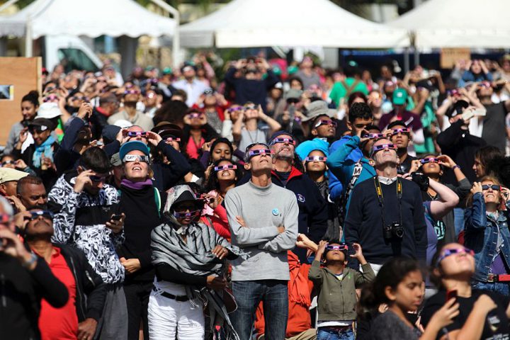 People look through eclipse viewing glasses, telescopes or photo cameras an annular solar eclipse, on September 1, 2016, in Saint-Louis, on the Indian Ocean island of La Reunion.
