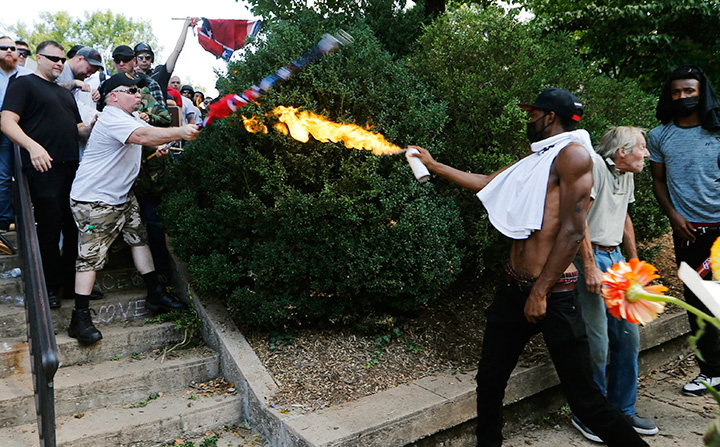 A counter demonstrator uses a lighted spray can against a white nationalist demonstrator at the entrance to Lee Park in Charlottesville, Va., Saturday, Aug. 12, 2017.