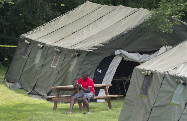 An asylum seeker checks his phone next to a tent at the Canada-United States border in Lacolle, Que. 