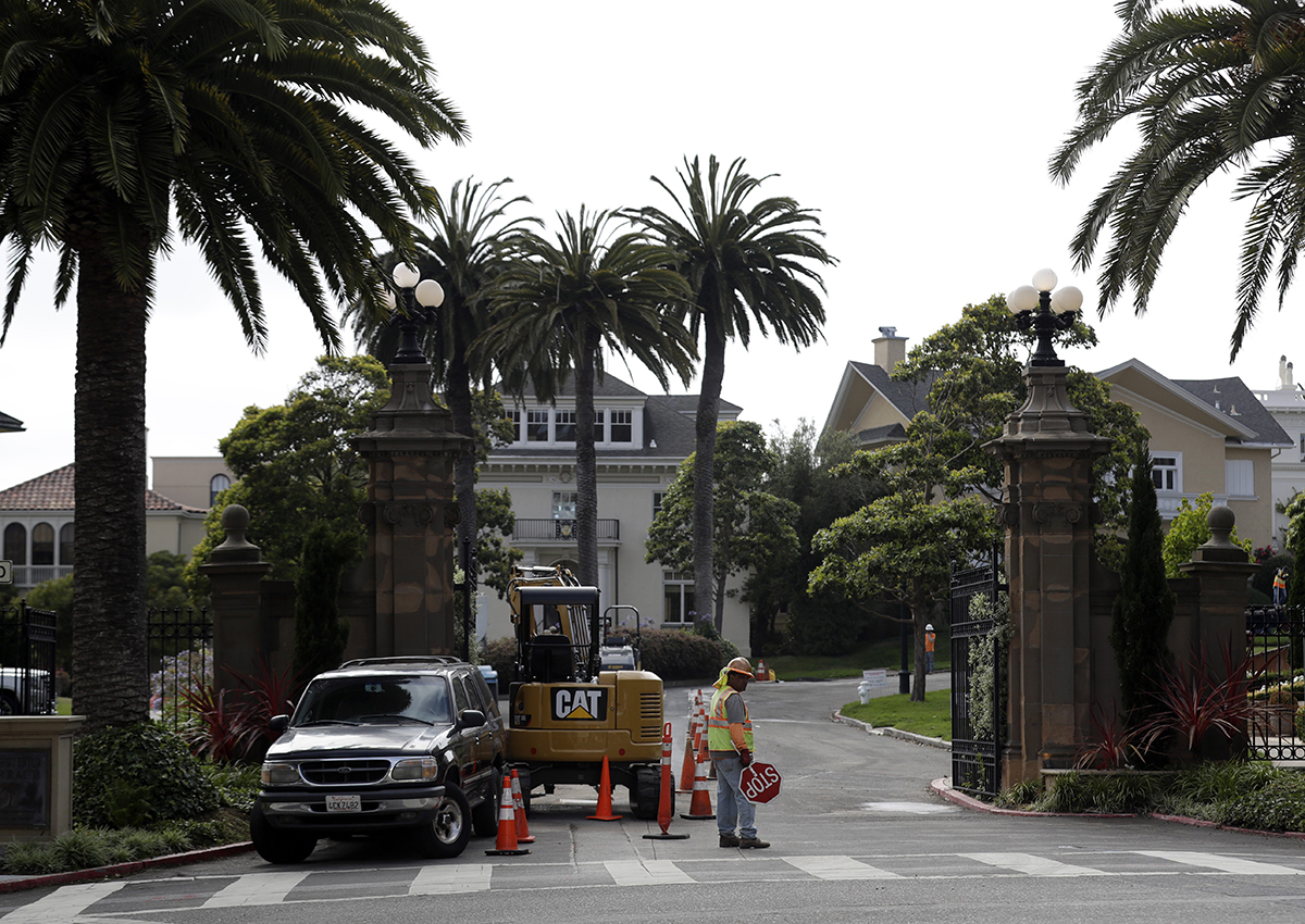 A construction workers stands in front of a gate leading into the Presidio Terrace neighborhood Monday, Aug. 7, 2017, in San Francisco.