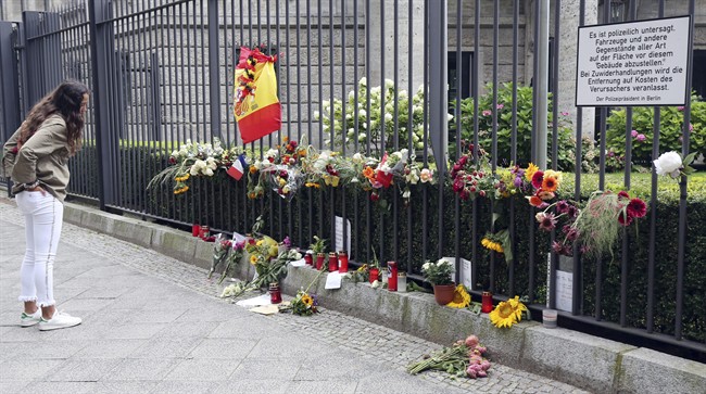 A woman looks at the symbols of condolence people have laid down for the victims of the terror attacks that killed 14 people and wounded over 120 in Barcelona , Spain, in front of the Spanish embassy in Berlin, Germany, Monday, Aug. 21, 2017. 