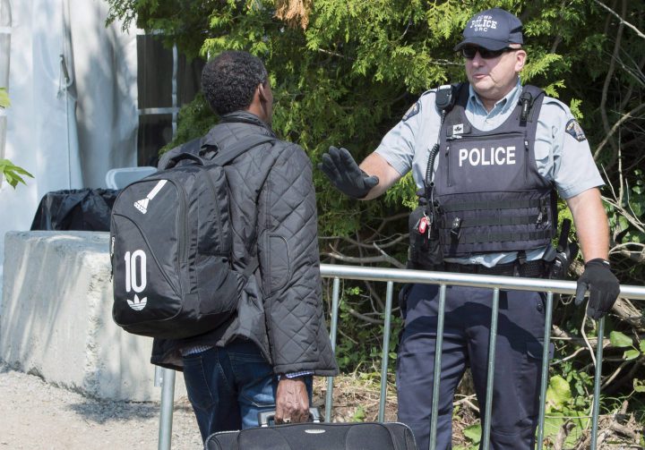 An asylum seeker, claiming to be from Eritrea, is questioned by an RCMP officer as he crosses into Canada. A new study looks at the likely implications of raising Canada's immigration target to 450,000 people a year, including refugees.