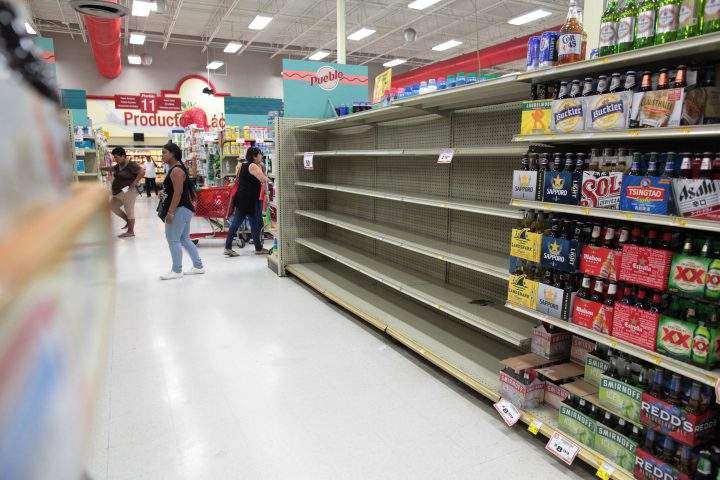 Customers walk near empty shelves that are normally filled with bottles of water after Puerto Rico Governor Ricardo Rossello declared a state of emergency.