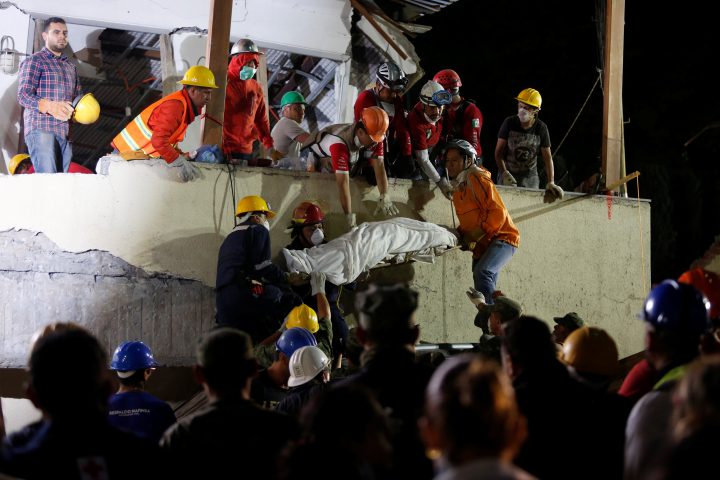 Rescue workers remove a dead body after searching through rubble in a floodlit search for students at Enrique Rebsamen school in Mexico City on Sept. 20, 2017.