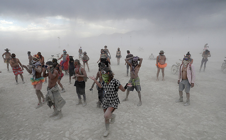 Burning Man participants dance in the midst of a driving desert dust storm on the 2nd day of the annual Burning Man arts and music festival in the Black Rock Desert of Nevada, August 29, 2017.