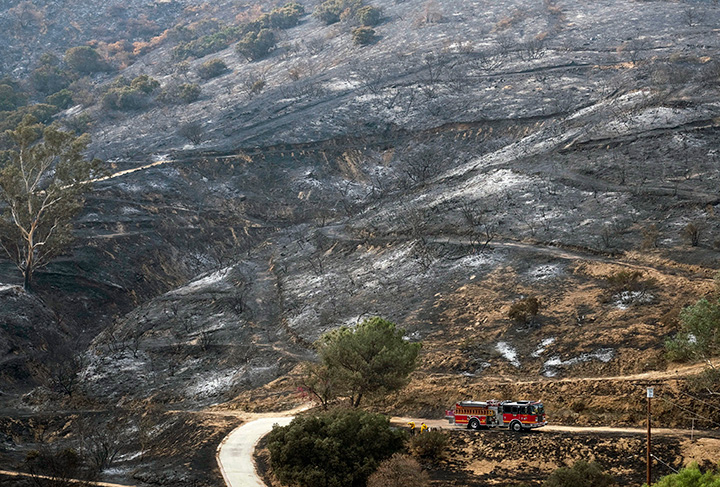 A fire engine drives past a burned area from a wildfire Monday, Sept. 4, 2017, in the Sunland-Tujunga section of Los Angeles.