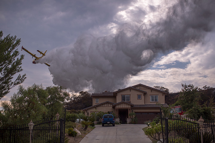 A Super Scooper CL-415 firefighting aircraft from Canada makes a drop to protect a house during the La Tuna Fire on September 3, 2017 near Burbank, California.