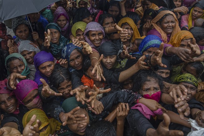 Rohingya Muslim women, who crossed over from Myanmar into Bangladesh, stretch their arms out to collect sanitary products distributed by aid agencies near Balukhali refugee camp, Bangladesh, Sunday, Sept. 17, 2017.
