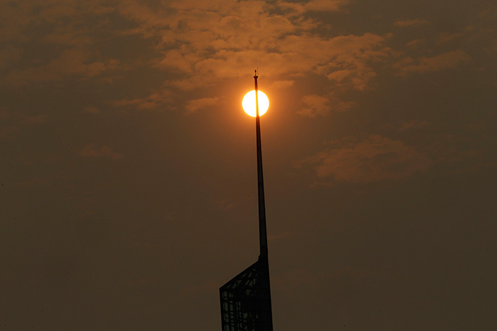 A glowing, orange sun, muted by wildfire smoke, is visible behind the spire of the Oregon Convention Center in Portland, Ore., Tuesday, Sept. 5, 2017.