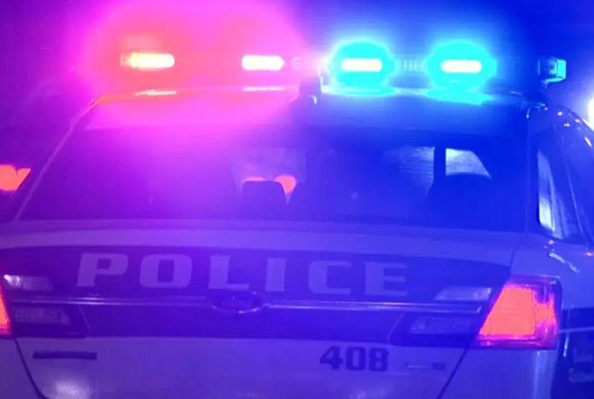 A Winnipeg police cruiser at night with flashing red and blue lights.