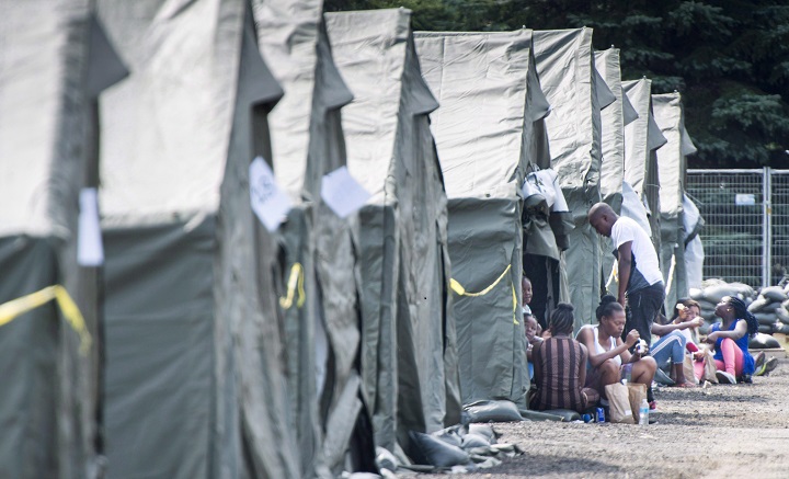 Asylum seekers sit in front of their tent in a temporary camp, Tuesday, August 15, 2017, near Saint-Bernard-de-Lacolle, Que.