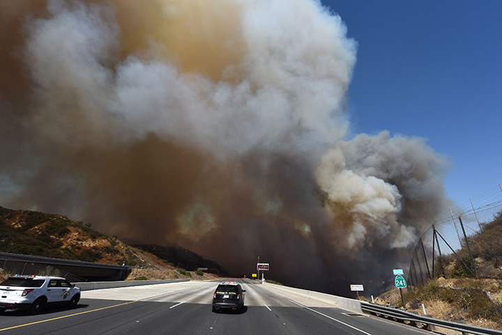 A police car blocks the 241 freeway as smoke from the Canyon 2 Fire covers the road near Orange, California, October 9, 2017.