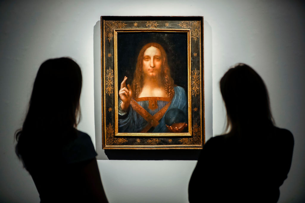 Christie's employees pose in front of a painting entitled Salvator Mundi by Italian polymath Leonardo da Vinci at a photocall at Christie's auction house in central London on October 22, 2017 ahead of its sale at Christie's New York on November 15, 2017. 