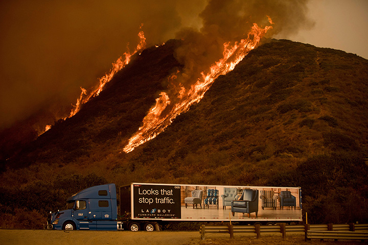Flames from the Thomas fire burn above a truck on Highway 101 north of Ventura, Calif., on Wednesday, Dec. 6, 2017.
