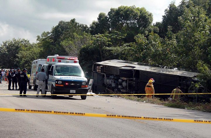 An ambulance sits parked next to an overturned bus in Mahahual, Quintana Roo state, Mexico, Tuesday, Dec. 19, 2017.