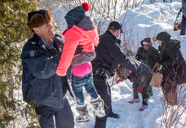Family members from Somalia are helped across the border into Canada from the United States Friday, February 17, 2017 near Hemmingford, Que.