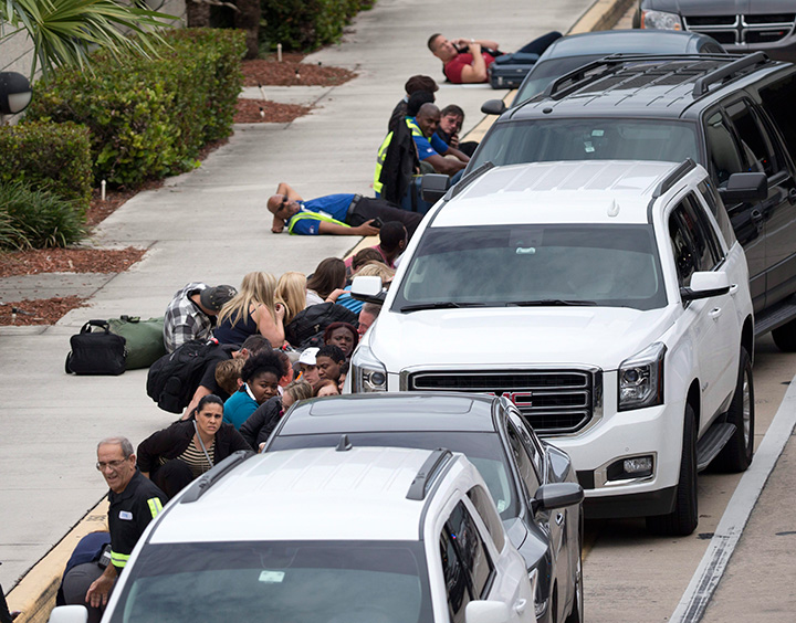 People take cover outside Hollywood International Airport in Fort Lauderdale, Fla., on Jan. 6, 2017, after a shooter opened fire inside a terminal at the airport.