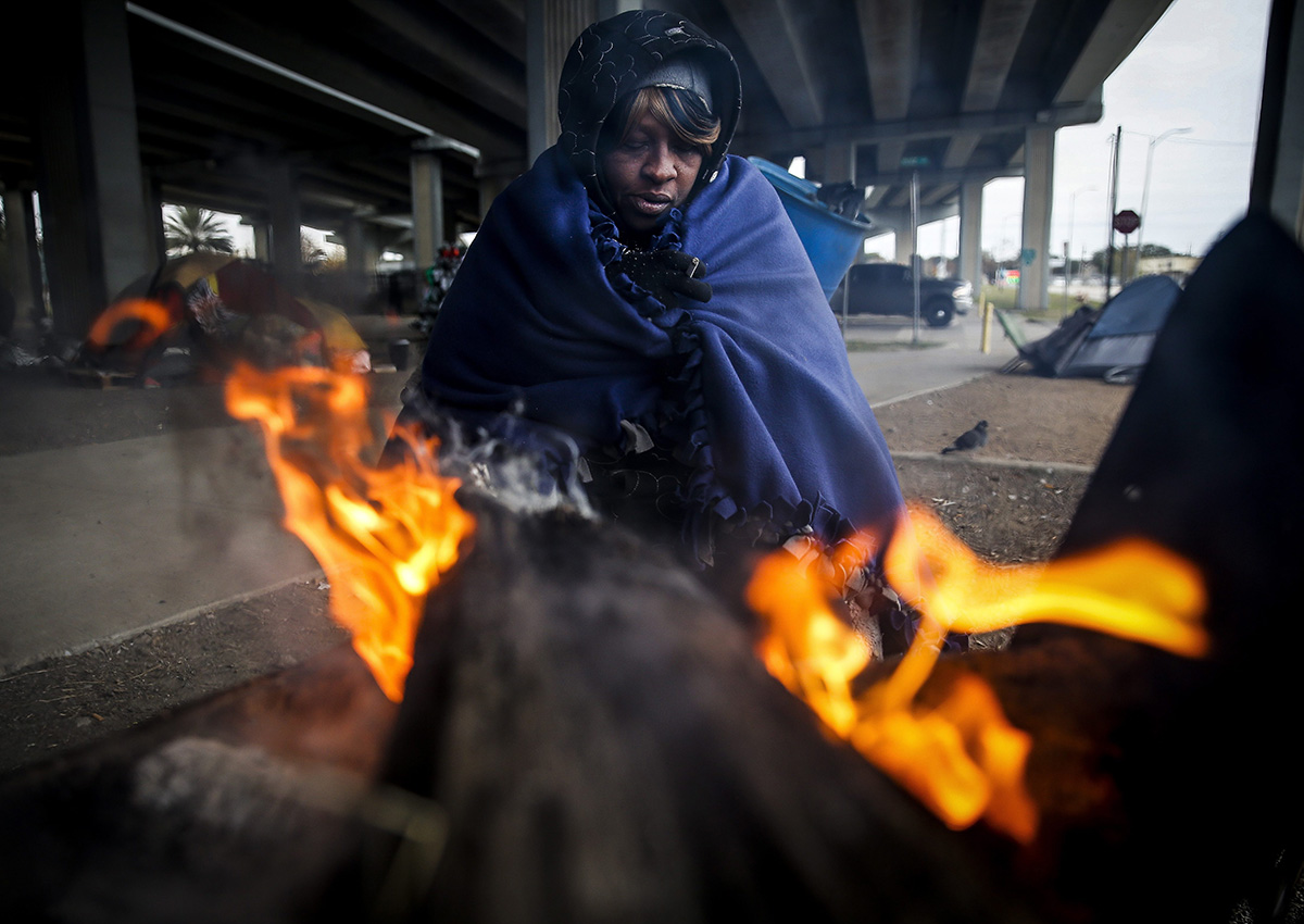 Tony Sampson, who received a blanket from Star of Hope’s Love in Action van, tries to warm up by a fire under the Eastex Freeway as temperatures hover in the 30s Tuesday, Jan. 2, 2018, in Houston.
