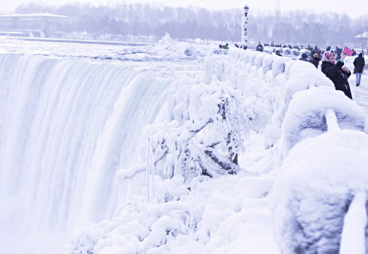 Visitors take photographs at the brink of the Horseshoe Falls in Niagara Falls, Ont., as cold weather continues through much of the province on Friday