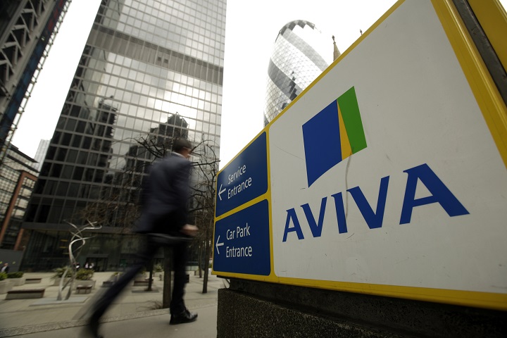 A pedestrian passes a sign outside the headquarters of Aviva Plc in London, U.K., on Friday, March 7, 2014.