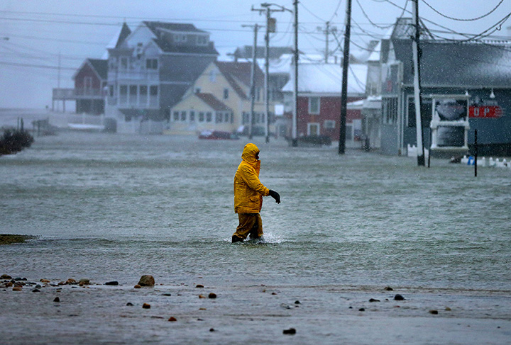 A man walks through a flooded section of Brant Rock in Marshfield, Mass., on Jan. 4, 2018.