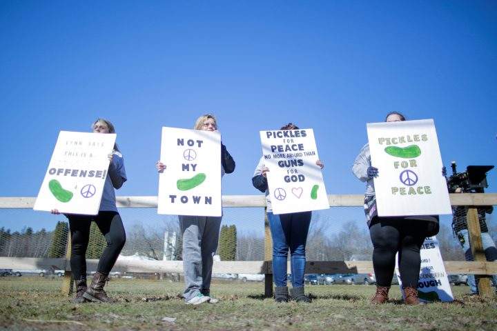People protest outside the church as worshipers attend a blessing ceremony with their AR-15-style rifles.
