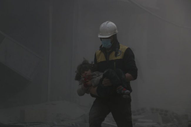 A Syrian civil defense team member carries a baby rescued from a wreckage after Assad regime forces carried out airstrikes over the de-escalation zone in Arbin town of Eastern Ghouta in Damascus, Syria on February 23, 2018.
