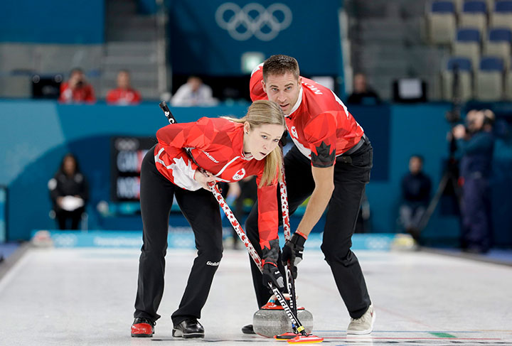 Canada’s Kaitlyn Lawes and John Morris sweep the ice during the mixed doubles semi-final curling match against Norway at the 2018 Winter Olympics in Gangneung, South Korea, Feb. 12, 2018.