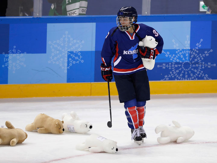 Korea’s team picks up stuffed animals tossed onto the ice after their game against Japan.