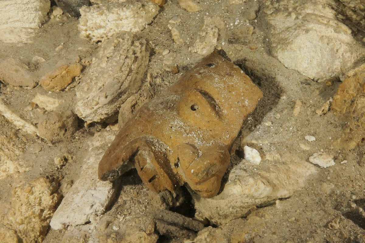 This undated photo released by Mexico’s National Anthropology and History Institute (INAH) shows a piece of a broken mask on the cave floor inside the Sac Actun underwater cave system where Mayan and Pleistocene bones and cultural artifacts have been found submerged, near Tulum, Mexico.