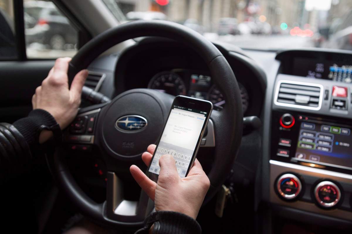 A driver texts while at the wheel in this photo illustration of distracted driving on Wednesday, Jan. 25, 2017 in Montreal.