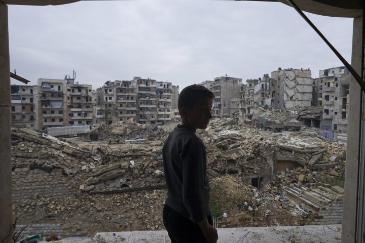In this picture taken Sunday, Jan. 21, 2018, a resident checks the destruction from his home balcony that was damaged by shelling in Aleppo, Syria.