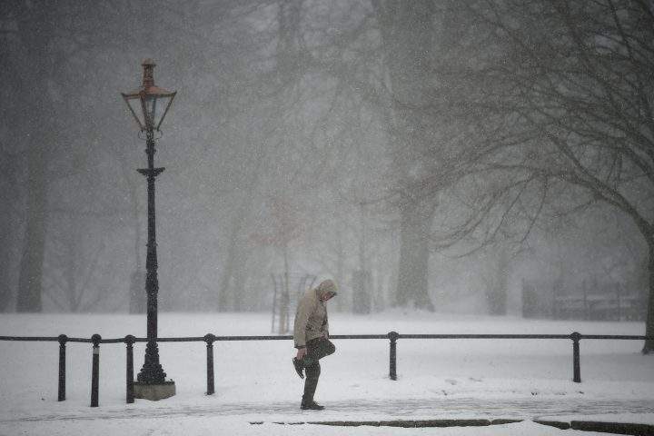 A man tries to clean his shoes in the snow at the Phoenix Park in Dublin, Ireland, Feb. 28, 2018.