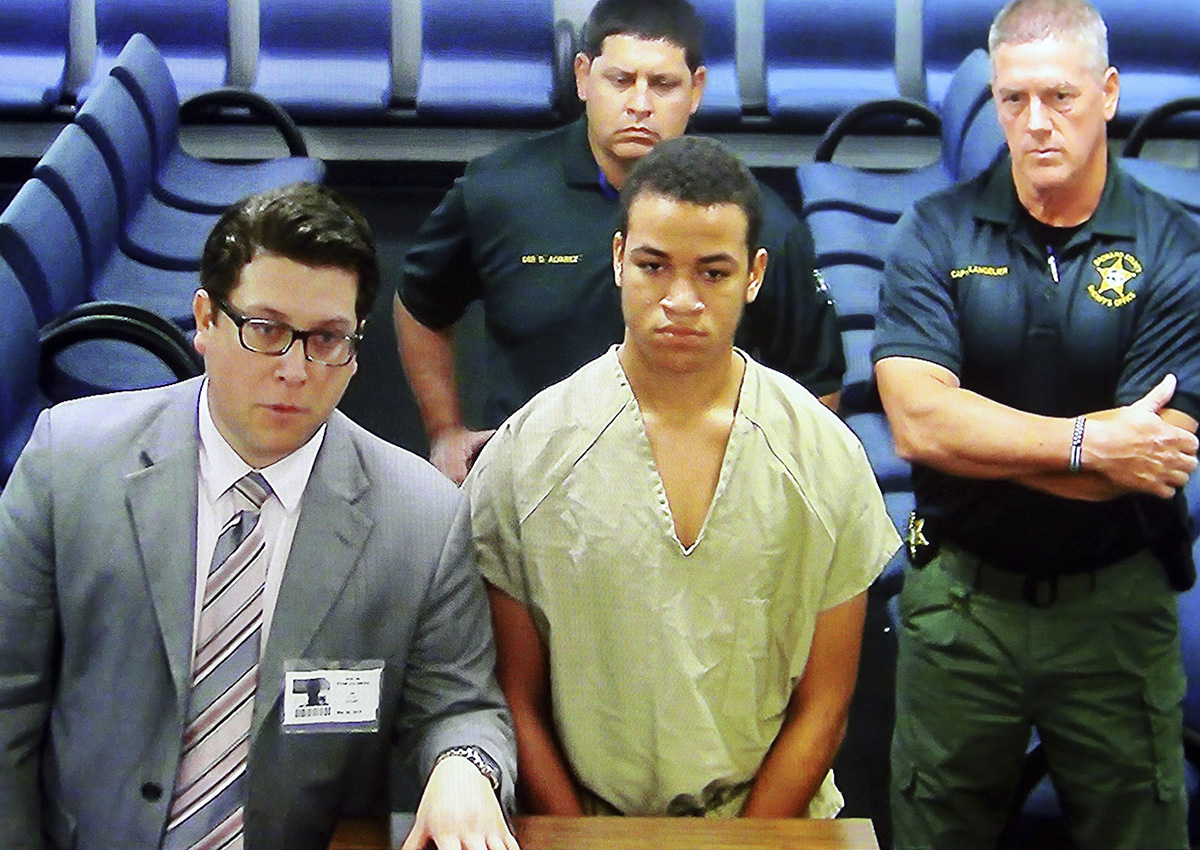 Zachary Cruz, center, the brother of the Florida school shooting suspect, is displayed in a monitor via closed circuit television from the main jail as he as he makes his first appearance on charges of trespassing on the grounds of Marjory Stoneman Douglas High School, Tuesday, March 20, 2018, at the Broward County Courthouse in Fort Lauderdale, Fla. 