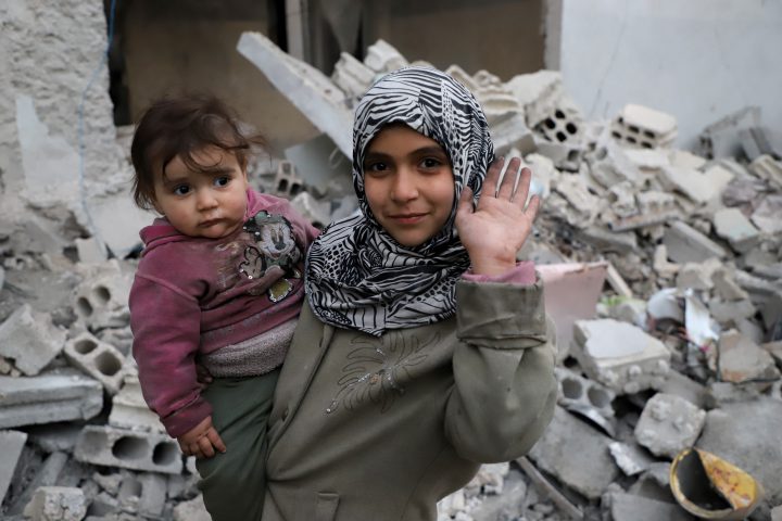 A Syrian girl raises her hand while she holds a baby in her arms for #Iamstillalive.