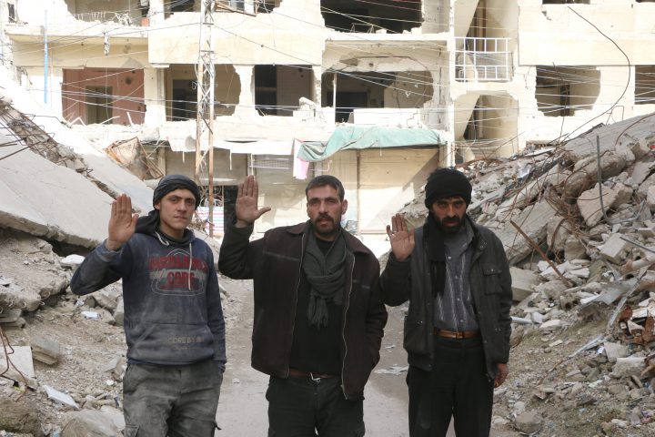 Syrian men raise their hands as they pose for a photo for #Iamstillalive.