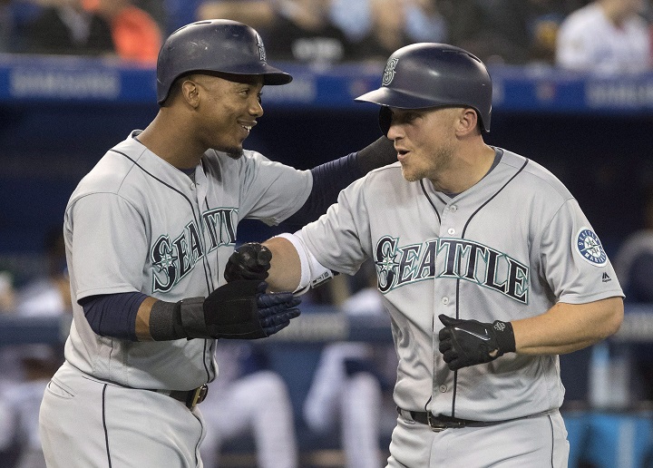 Seattle Mariners' Kyle Seager celebrates with teammate Jean Segura after hitting a grand slam against Toronto Blue Jays starting pitcher J.A. Happ in first inning League MLB baseball action in Toronto on Thursday.