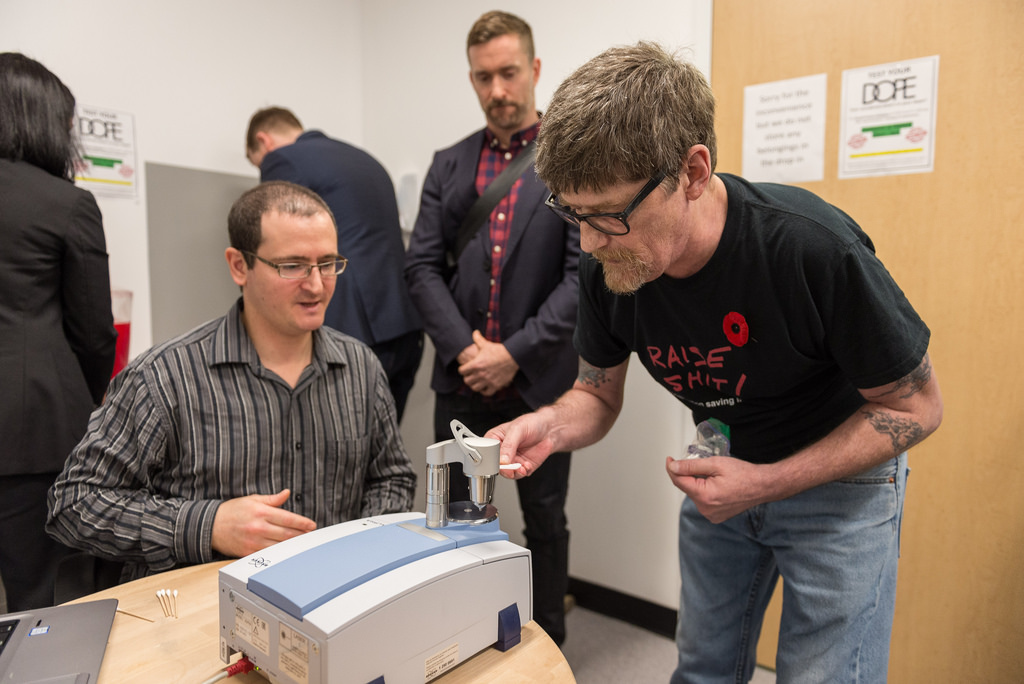 Health workers use an FTIR spectrometer to test drug samples.
