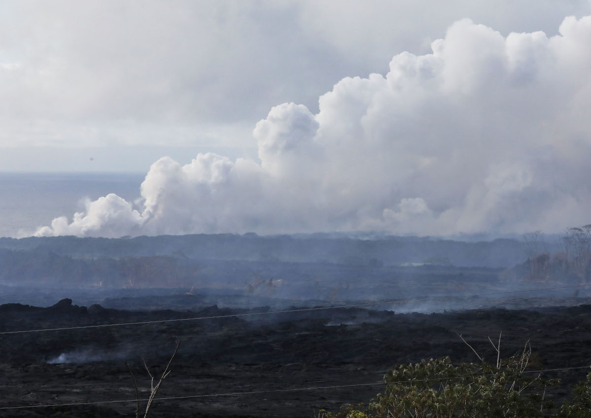 A steam plume rises (TOP) from lava entering the Pacific Ocean, after flowing to the water from a Kilauea volcano fissure, on Hawaii’s Big Island on May 20, 2018 in Kapoho, Hawaii.