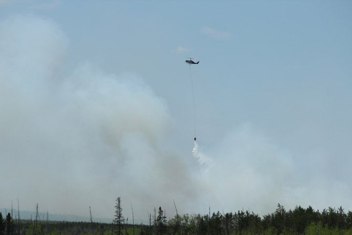 An aerial unit drops water on a wildfire burning out of control near Holbein, Sask.