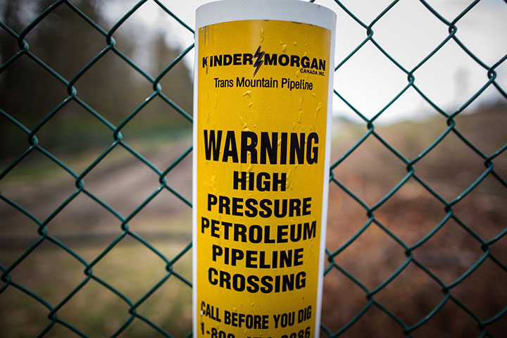 A sign warning of an underground petroleum pipeline is seen on a fence at Kinder Morgan's facility where work is being conducted in preparation for the expansion of the Trans Mountain Pipeline, in Burnaby, B.C., on Monday April 9, 2018. 