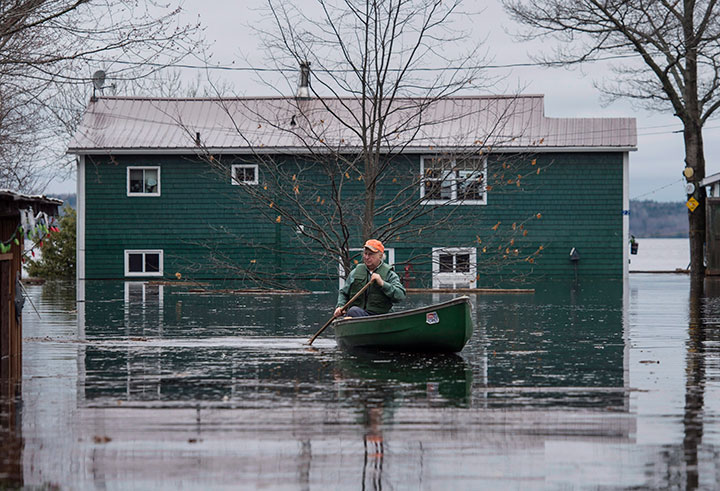 A man paddles in front of a flooded home on Grand Lake, N.B. as floodwaters continue to rise from the Saint John River on Tuesday, May 1, 2018.