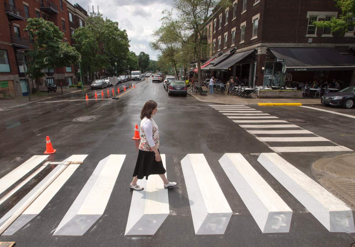 A pedestrian walks a crosswalk painted in a 3-dimensional style for a pilot project, in the Montreal borough of Outremont on Tuesday, July 10, 2018.