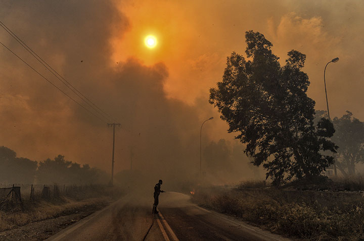 A firefighter tries to extinguish hotspots during a wildfire in Kineta, near Athens, on July 23, 2018.