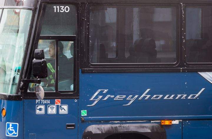 A worker moves a Greyhound bus after it was washed, in Vancouver, on July 9, 2018.