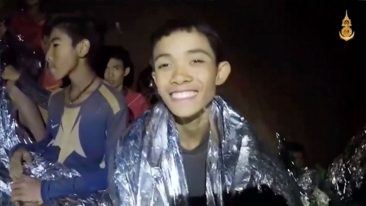 In this July 3, 2018 image taken from video provided by the Royal Thai Navy Facebook Page, a Thai boy smiles as Thai Navy SEAL medic help injured children inside a cave in Mae Sai, northern Thailand.