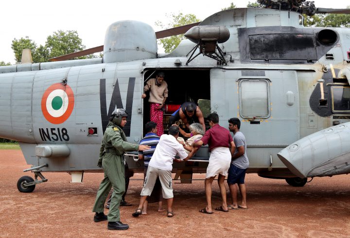 People help a woman disembark from an Indian Navy helicopter at a relief camp after being rescued from a flooded area in the southern state of Kerala, India, August 17, 2018.