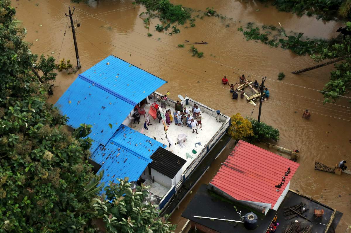 People wait for aid on the roof of their house at a flooded area in the southern state of Kerala, India, August 17, 2018.